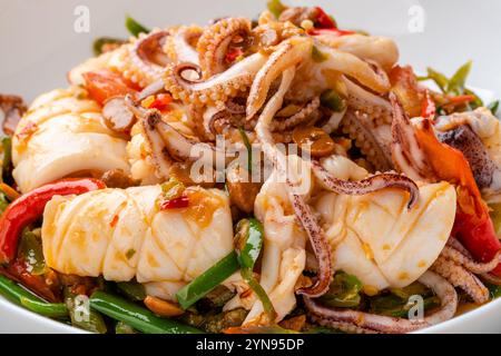 Tumis Cumi tauco ou Squid Stir Fried épicé avec tauco servi sur assiette blanche et isolé sur fond gris. Tauco est une pâte faite à partir de fer conservé Banque D'Images