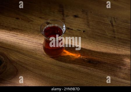 Tisane dans un verre délicat brille brillamment dans la lumière chaude de l'après-midi sur une table en bois. Banque D'Images