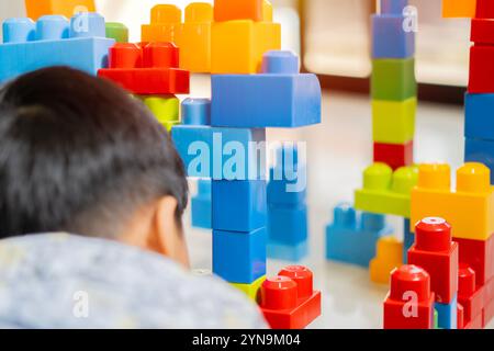 Vue arrière d'un garçon d'enfant asiatique jouant avec des blocs de construction à l'école. Mise au point sélective. Concept de jouet éducatif. Banque D'Images