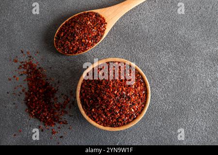 Flocons de poivron rouge. Piments rouges dans un bol en bois sur fond gris. Piments secs Banque D'Images