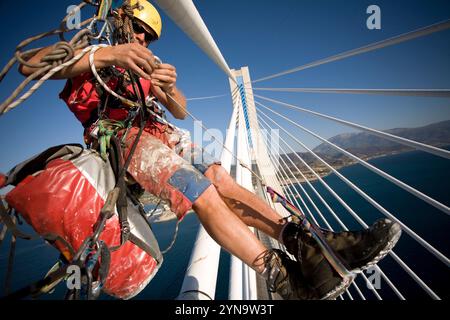 Un homme travaillant sur le maintien de la plus longue du monde pont suspendu à haubans pont près de Patras, Grèce. Banque D'Images