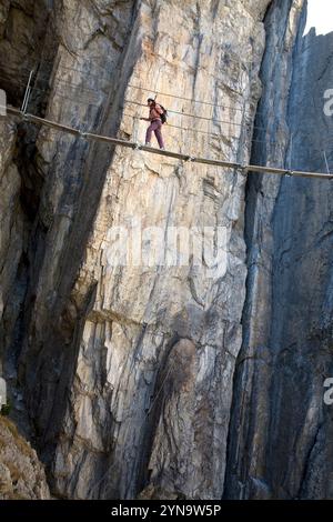 Une jeune femme marche sur un pont tout en s'engageant dans le sport de la Via Ferrata de Val d'isère, Savoie, France. Banque D'Images