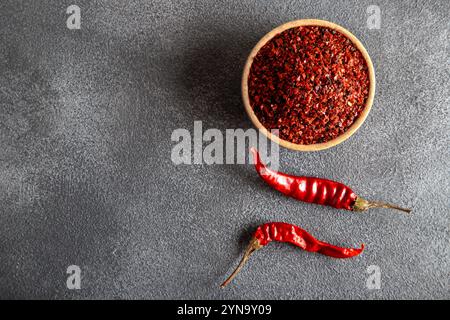 Flocons de poivre. Piments rouges dans une cuillère en bois sur fond noir. Piments secs Banque D'Images