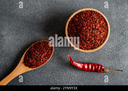 Flocons de poivron rouge. Piments rouges dans un bol en bois sur fond gris. Piments secs Banque D'Images