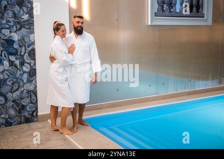 Jeune couple heureux profite au centre de spa près de la piscine. Homme et femme en vacances. Banque D'Images