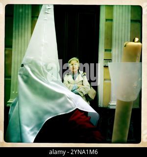 Un wooman regarde un pénitent tenant une bougie pendant une procession de la semaine Sainte de Pâques à Puente Genil, province de Cordoue, Andalousie, Espagne, 4 avril, 2012. Banque D'Images