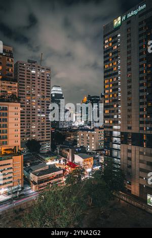 Une vue nocturne du paysage urbain animé de Bangkok, avec des bâtiments illuminés, des rues animées et des feux de circulation colorés Banque D'Images