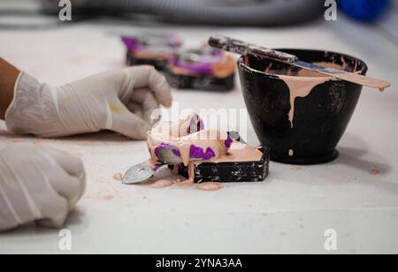 Una persona prépara un molde Dental con una masa de color morado en el laboratorio Banque D'Images