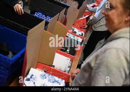 Hambourg, Allemagne. 25 novembre 2024. Les assistants emballent des colis avec de la nourriture, des jouets et des vêtements au Centre de logistique sociale. Pour Noël, le pacte de ville '#HamburgKyiv' aimerait envoyer 4 000 colis de Noël 'amour dans une boîte' pour enfants avec des jouets, des vêtements, des articles d'hygiène et d'autres articles de tous les jours à Kiev avec le soutien de la ville, des entreprises et des associations caritatives. Crédit : Niklas Graeber/dpa/Alamy Live News Banque D'Images