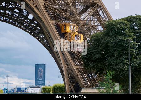 France, Paris, zone classée au Patrimoine mondial de l'UNESCO, les ascenseurs de la Tour Eiffel lors des Jeux Olympiques de 2024 avec, en arrière-plan, la photo géante du nageur Léon Marchand sur la Tour Montparnasse Banque D'Images