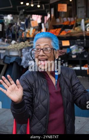 Une femme plus âgée, peut-être dans la soixantaine, avec des cheveux cyan bleu vif. Au défilé Dominicain Day sur la 37e Avenue à Jackson Heights, Queens. Banque D'Images