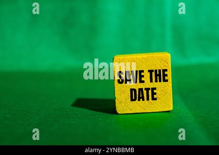 Enregistrez le message de date écrit sur un cube en bois jaune avec fond vert. Conceptuel enregistrer le symbole de date. Copier l'espace. Banque D'Images