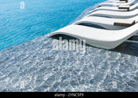 Une piscine avec une chaise longue blanche sur le bord. La chaise est sur le côté de la piscine, et il est positionné dans l'eau. La piscine est entourée d'un blu Banque D'Images