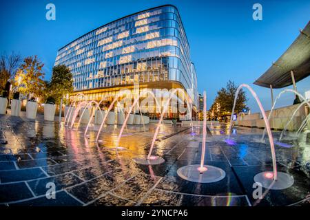 WASHINGTON DC, États-Unis — des fontaines interactives et des plans d'eau animent les espaces plaza du Wharf, un quartier riverain réaménagé dans le sud-ouest DC, alors que le crépuscule s'installe sur le développement à usage mixte. Les bâtiments modernes encadrent les expositions aquatiques, qui offrent à la fois un attrait esthétique et des espaces de rassemblement publics. Banque D'Images