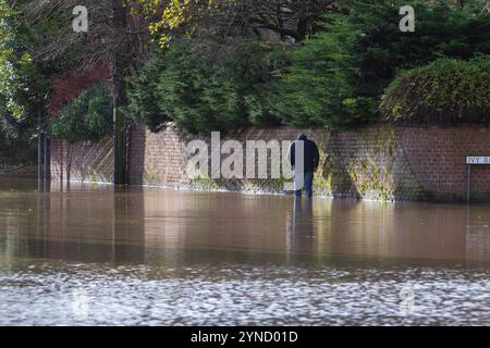 Chippenham, Wiltshire, Royaume-Uni, 25 novembre 2024. Un homme est photographié marchant sur le sentier inondé d'une route inondée dans le centre-ville de Chippenham, de nombreuses routes menant à Chippenham ont été inondées après que la rivière Avon dans la ville a éclaté ses rives. Crédit : Lynchpics/Alamy Live News Banque D'Images