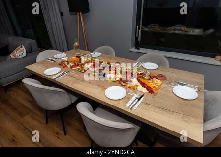 Divers fromages et charcuterie étalés sur la table sur du papier cuisson, soirée à la maison. Banque D'Images