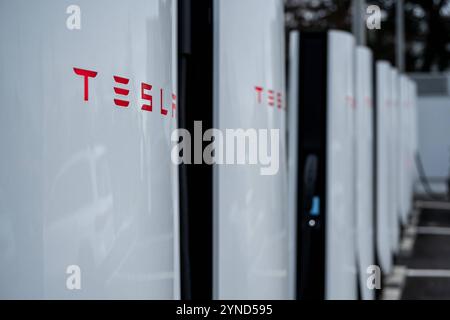 Tesla Supercharger-Ladestationen in einer Reihe 25.11.24, Limbourg : Symbolfoto, Illustrationsbild, Symbolbild, Illustrationsfoto, Alltagsszene Tesla Supercharger-Ladestationen in einer Reihe Nahaufnahme mehrerer Tesla Supercharger-Ladestationen, die in einer Reihe aufgestellt sind. Die weißen Säulen mit dem roten Tesla-logo befinden sich auf einem Parkplatz unter freiem Himmel. IM Hintergrund sind Bäume und eine technische Anlage zu sehen. . Limburg Hessen Allemagne *** Tesla Supercharger stations dans une rangée 25 11 24, Limburg symbole photo, illustration image, symbole image, illustration pho Banque D'Images