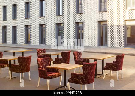 Café d'été dans la rue. Chaises et tables sont dans la rue devant un bâtiment en briques blanches avec de grandes fenêtres. Banque D'Images