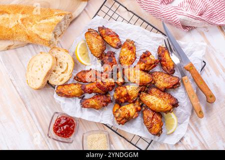 Ailes de poulet marinées et grillées avec citron, ail, graines de sésame et baguette fraîche Banque D'Images