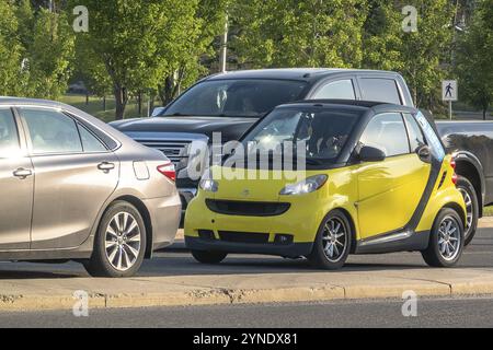 Calgary, Alberta, Canada. 12 juillet 2024. Une Smart jaune fortwo une voiture compacte arrêtée dans la circulation Banque D'Images