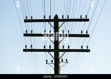 Vieux poteau en bois avec des fils électriques sur un fond de ciel clair Banque D'Images