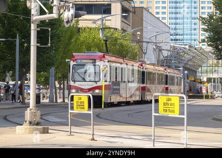 Calgary, Alberta, Canada. 5 août 2024. Un CTrain rouge et blanc Calgary transit navigue à une intersection de ville, avec ProMinent Banque D'Images