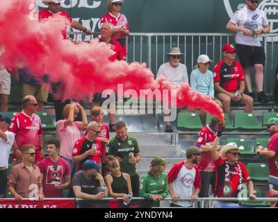 Calgary, Alberta, Canada. 17 juillet 2023. Un fan de football tenant une bombe fumigène couleur pendant un match. Concept : passion des fans, foules lors d'événements sportifs Banque D'Images