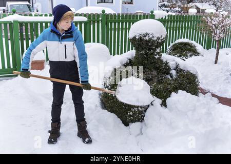 Adolescent déneigement, 16 ans, neige déneigée loin d'une maison, déneigement en hiver, pelle à neige, tir studio de déneigement, fédéral Banque D'Images