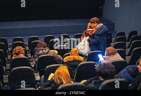 garçon avec pop-corn cherchant son siège avant de regarder un film dans un cinéma. journée en famille Banque D'Images