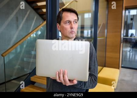 17 novembre 2024 : un homme réfléchi avec un ordinateur portable à la main. Image symbolique pour l'intimidation et le discours de haine au travail ou dans l'environnement numérique *** Ein nachdenklicher Mann mit einem Laptop in der Hand. Symbolbild für Mobbing und Hatespeech am Arbeitsplatz oder im digitalen Umfeld Banque D'Images