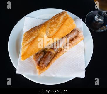 Le snack copieux est une baguette croustillante farcie de saucisses grasses juteuses et d'oignons passionnés. Banque D'Images