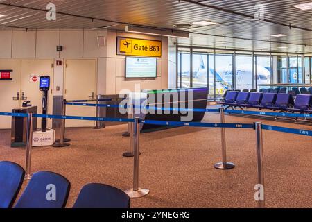 Porte d'embarquement vide à l'aéroport international Newark Liberty, porte B63, avec sièges bleus et avion d'attente à l'extérieur. New Jersey, États-Unis. Banque D'Images