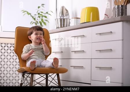 Petit garçon jouant sur la chaise dans la cuisine. Situation dangereuse Banque D'Images