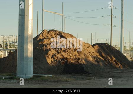 Vue large près du coucher du soleil Grande pile de terre sur la droite de la sous-station électrique avec lignes de poteau haute puissance à nouveaux Petersburg, Floride. Clôture temporaire en liasse Banque D'Images