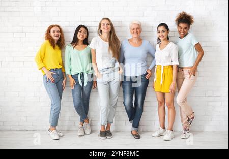 Diverses femmes de différentes âges se tenant sur le mur blanc de brique Banque D'Images