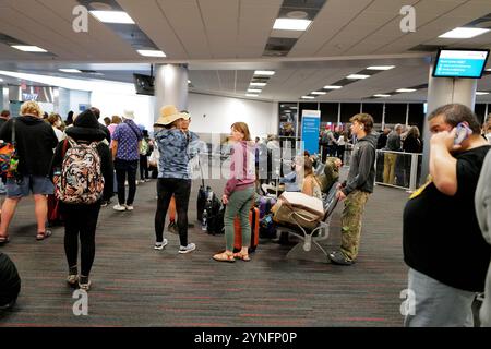 Les passagers se rassemblent dans le terminal de l'aéroport de Miami, assis et debout, attendant les vols dans un espace animé mais calme rempli de voyageurs, de bagages. Banque D'Images