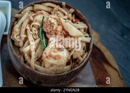 La cuisine thaïlandaise épicée, pousses de bambou sautées avec boule de poisson dans un bol en bois. Vue oblique d'en haut. Banque D'Images