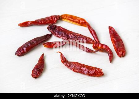 Piments rouges séchés dispersés sur une surface en bois. Banque D'Images