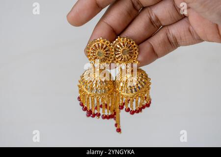 Une paire de belles boucles d'oreilles vintage plaquées or est affichée dans la main d'une femme. Banque D'Images
