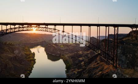 Un pont enjambe une rivière avec un coucher de soleil en arrière-plan Banque D'Images