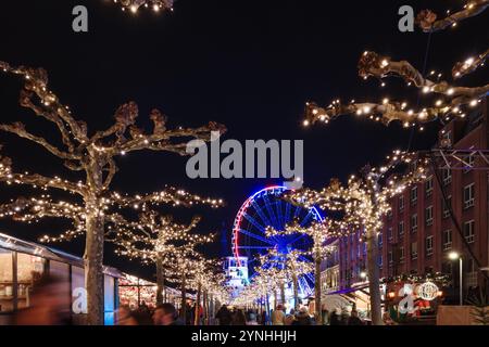 Paysage de nuit sur la promenade et la passerelle le long de la rivière Rhin et étal de marché avec fond de grande roue du marché de Noël, Weihnachts Banque D'Images