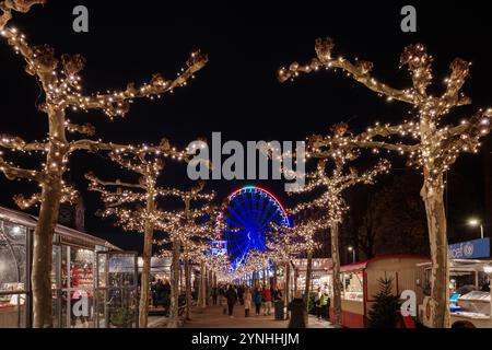 Paysage de nuit sur la promenade et la passerelle le long de la rivière Rhin et étal de marché avec fond de grande roue du marché de Noël, Weihnachts Banque D'Images