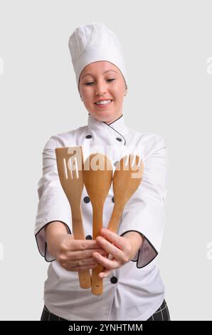 Chef professionnel tenant des ustensiles de cuisine en bois, souriant, prêt à cuisiner Banque D'Images