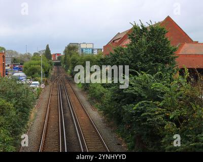 Poole, Dorset, Angleterre. 2 octobre 2024. Paysage avec des voies de chemin de fer jumelles droites flanquées d'arbres de chaque côté. Banque D'Images