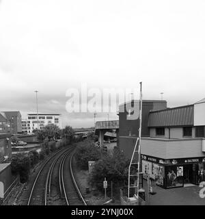 Poole, Dorset, Angleterre. 2 octobre 2024. Vue en niveaux de gris depuis une passerelle de la voie ferrée qui passe devant la boutique Saltrock. Banque D'Images