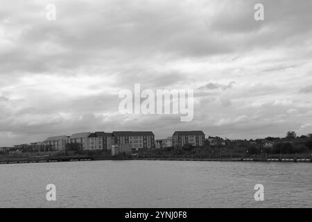 Poole, Dorset, Angleterre. 2 octobre 2024. Paysage en niveaux de gris des blocs d'appartements au bord de l'eau. Banque D'Images