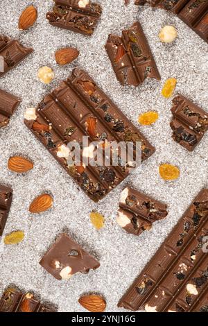 Morceaux de chocolat cassés avec des noix et des raisins secs sur une vue de dessus de fond en pierre Banque D'Images