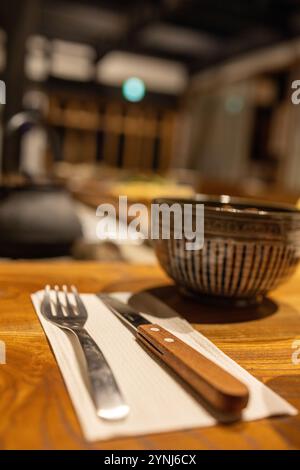 Gros plan de la table rustique avec fourchette, couteau et bol en céramique japonais Banque D'Images