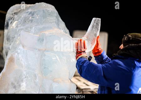 Oberhausen, Allemagne. 26 novembre 2024. Un artiste attache une corne à une sculpture de taureau lors d'une exposition de sculptures sur glace et neige, Centro Oberhausen. Crédit : Christoph Reichwein/dpa/Alamy Live News Banque D'Images