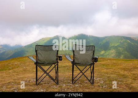 Deux charis de camping sur les collines et montagnes brumeuses sur le fond. Camping dans les montagnes concept photo. Banque D'Images